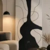 Modern black and cream abstract canvas wall art featuring a bold sculptural silhouette with flowing contour lines.